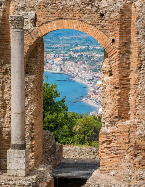 Ruins of the Ancient Greek Theater in Taormina with the sicilian coastline. Province of Messina, Sicily, southern Italy.