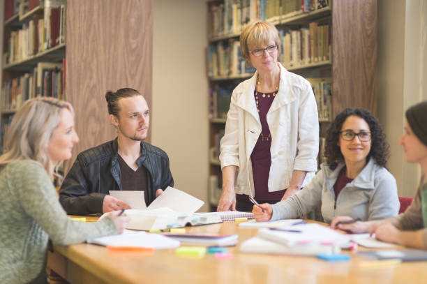 istock Female professor helping college study group in the library 1126539041