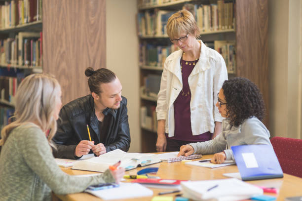 istock Female professor helping college study group in the library 1126539067