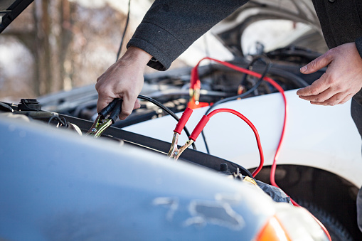 Man Helping a Stranger With an Empty Car Battery using Jumper Cables.