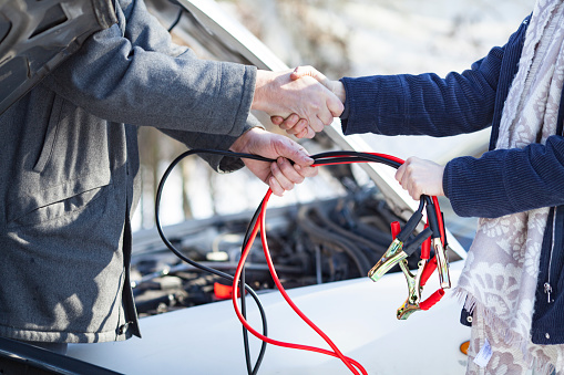Adult Woman Showing Gratitude with a Handshake After Getting Help With Car Battery in the Winter.
