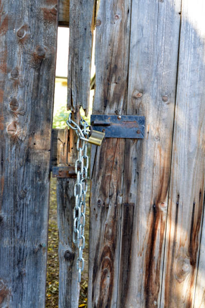 istock A latch, a padlock and a chain on a rotten wooden door 1126558477