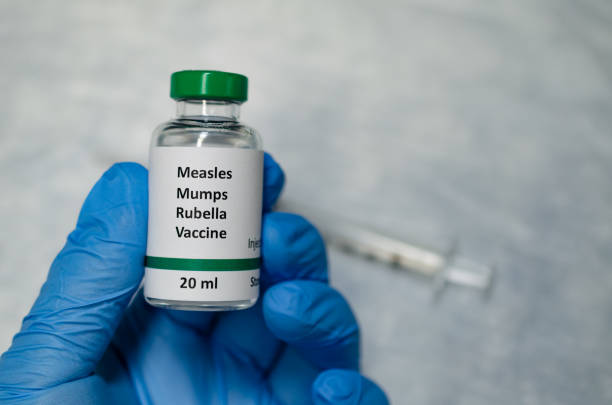 MMR vaccine holding in hand with injection syringe at the background A fake MMR vaccine vial holding in hand measles stock pictures, royalty-free photos & images