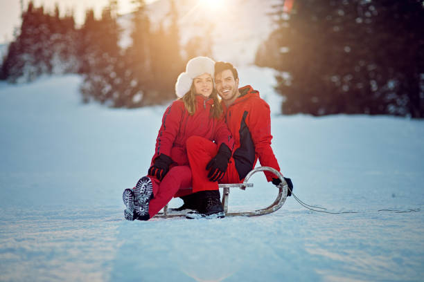 młoda para przytula się na sankach i cieszy się widokiem - skiing snow couple mountain zdjęcia i obrazy z banku zdjęć