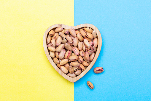 Pistachios in wooden Plate on Blue &Yellow Backgrounds