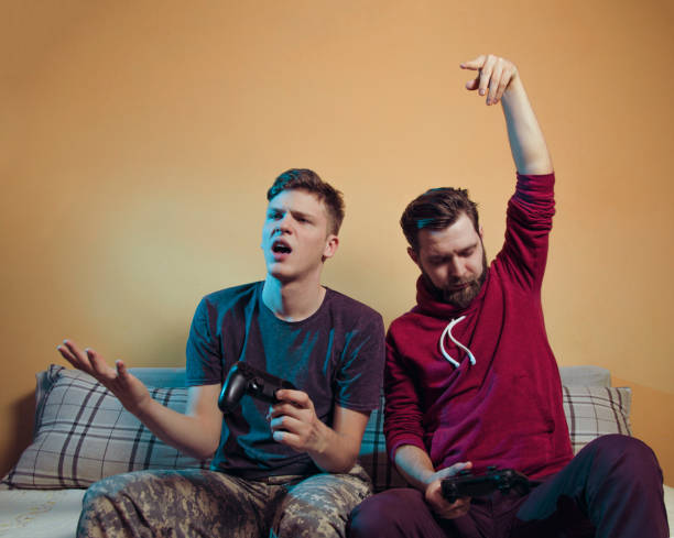 istock Man teasing teenage brother while playing video games 1126562883