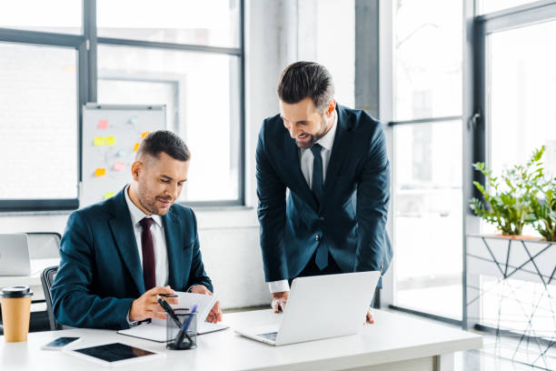 istock handsome businessman looking at coworker in modern office 1126564430