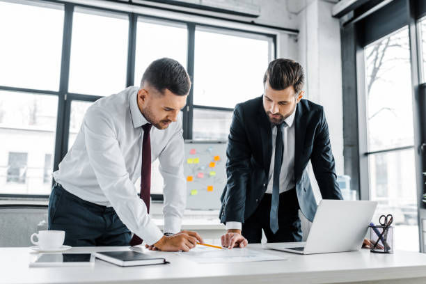 istock confident businessmen having discussion while standing near desk in modern office 1126564884