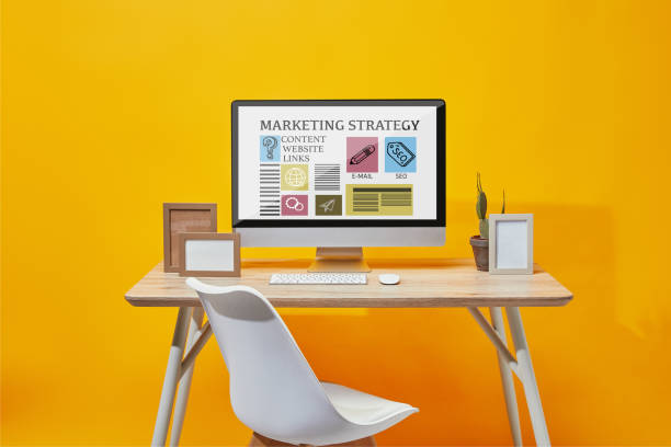 istock Computer with marketing strategy website on screen at wooden table on yellow background 1126565159