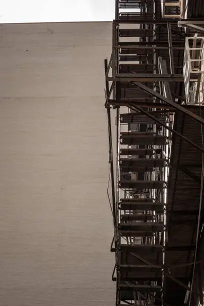 Photo of Fire escape stairs and ladder, in metal, on a typical North American old brick building from Montreal, Quebec, Canada. These stairs, made for emergency, are symbolic of the architecture