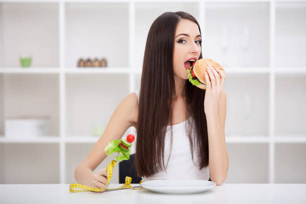 istock Attractive young woman makes a choice between healthy and unheal 1126572098