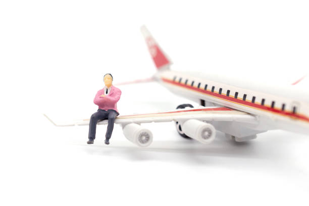 istock Miniature businessman sitting on airplane wing on white background 1126573520