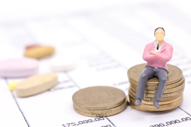 istock Miniature businessman and stack coins on statement and the drug behind. saving concept. 1126573547