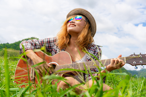 Happy woman plays guitar with nature background. Music and relaxation concept.