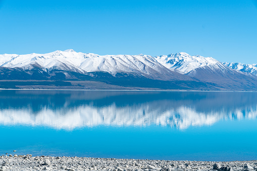 Snow capped mountains reflected in tranquil scenic Lake Pukaki in Mackenzie Basin Canterbury,NZ