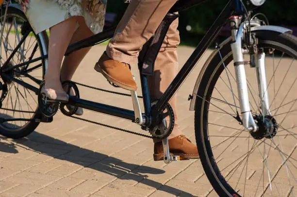 The couple man and woman ride tandem bike on the road