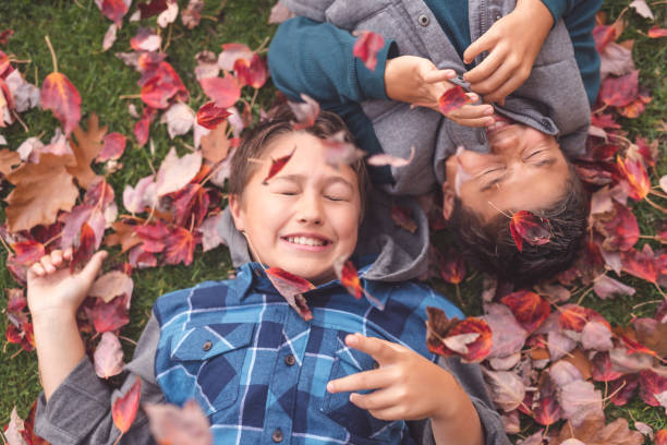 istock Two elementary-age brothers lay in the leaves at the park 1126588851