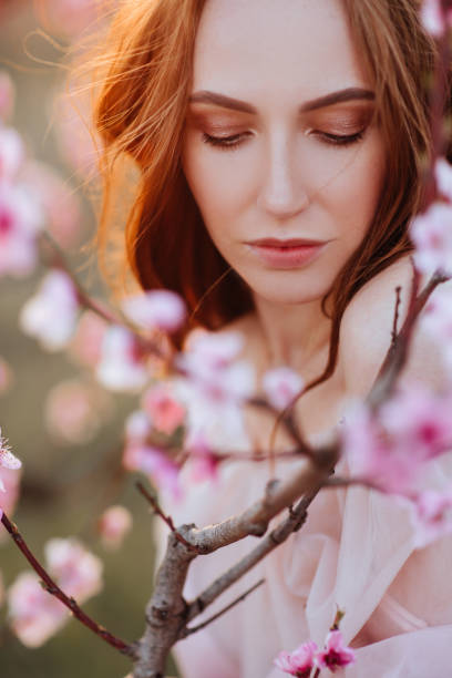istock Beautiful young girl under the flowering pink tree 1126588916
