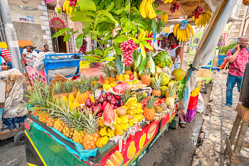 Vendor sells tropical fruits at a fruit stand in downtown Montego Bay, Jamaica on a cloudy day.