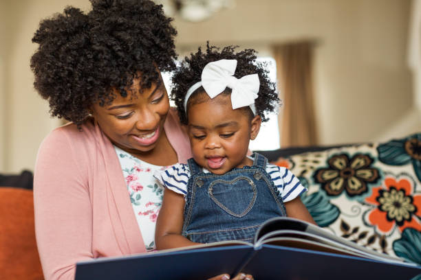 mother reading a book to her little girl. - family reading african descent book imagens e fotografias de stock