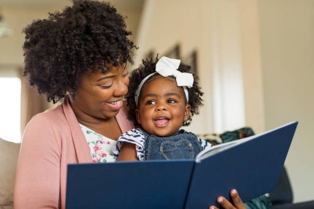 lecture d’un livre à sa petite fille de la mère. - family reading african descent book photos et images de collection