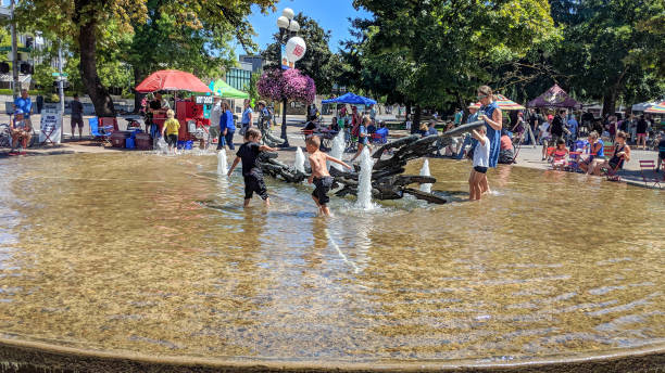 Eugene, Oregon, USA - July 29, 2018: A public gathering in Eugene, Oregon as people enjoy different venues and kid's have fun playing in water fountain. stock photo