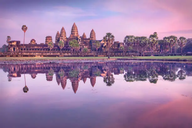 Angkor Wat temple at dramatic sunrise reflecting in water