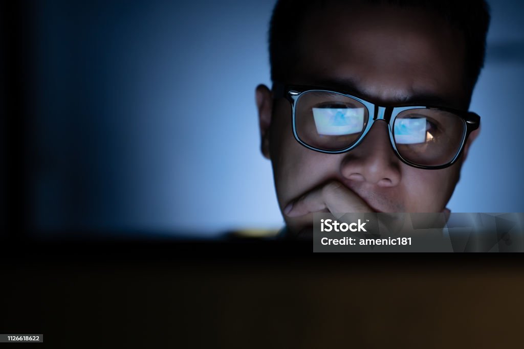 Ein fokussierter und seriös aussehender Mann, der hart am Computer arbeitet und denkt - Lizenzfrei Computerbildschirm Stock-Foto