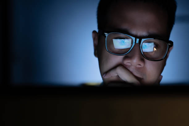 A focused and serious looking man working and thinking hard on a computer A focused and serious looking man working and thinking hard on a computer eye reflection stock pictures, royalty-free photos & images