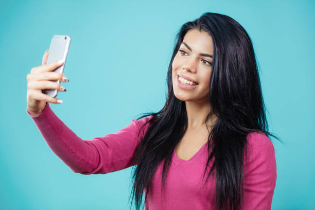 istock attractive woman with black hair using her smartphone for selfie 1126623732