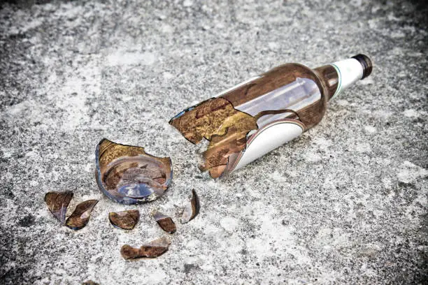 Photo of Shattered beer bottle resting on the ground - alcoholism concept image with copy space