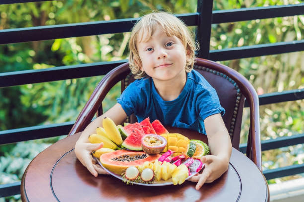 le garçon est de manger des fruits différents sur la terrasse - 7679 photos et images de collection