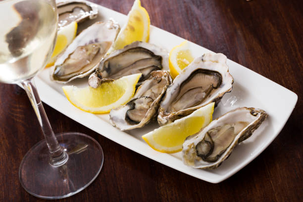 istock Tasty oysters with lemon on plate top view 1126626455