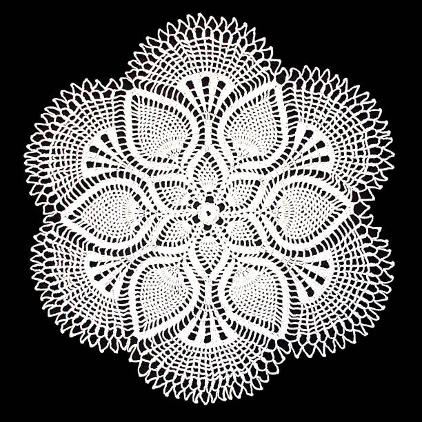 Isolated crocheted white doily with a pattern of cones on a black background. Round decorative doily. Isolated crocheted white doily with a pattern of cones on a black background. Round decorative cotton doily. Top view doily stock pictures, royalty-free photos & images