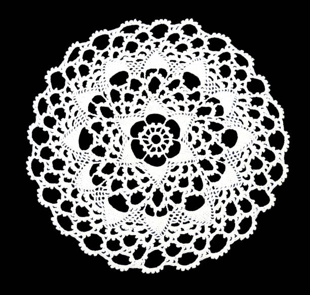 Isolated crocheted laced white doily with many picos at the egde on a black background. Round decorative cotton doily Isolated crocheted laced white doily with many arches and picos at the egde on a black background. Round decorative cotton doily. Top view doily stock pictures, royalty-free photos & images