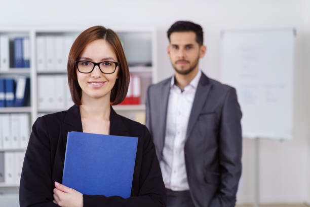 istock Woman holding blue folder with man in background 1126628982