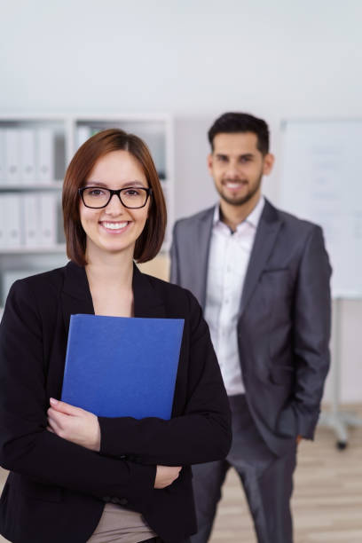 istock Smiling woman with folder and man in background 1126628986