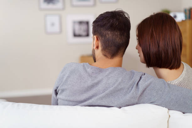 istock Young couple sitting arm in arm on a sofa 1126630641