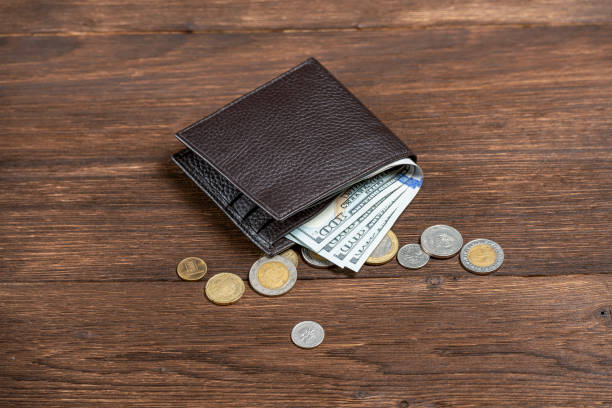 istock leather wallet with dollars on a wooden background with pennies 1126632098