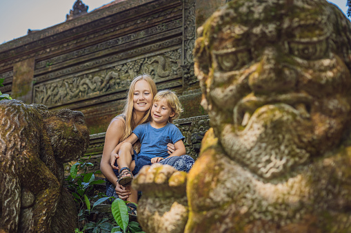 Mom and son travelers discovering Ubud forest in Monkey forest, Bali Indonesia. Traveling with children concept.