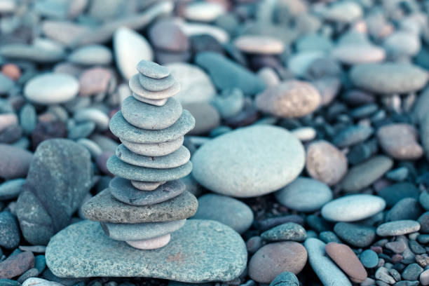 istock Stack of stones on beach - nature background. Stone cairn on green blurry background, pebbles and stones. Concept balance 1126638249