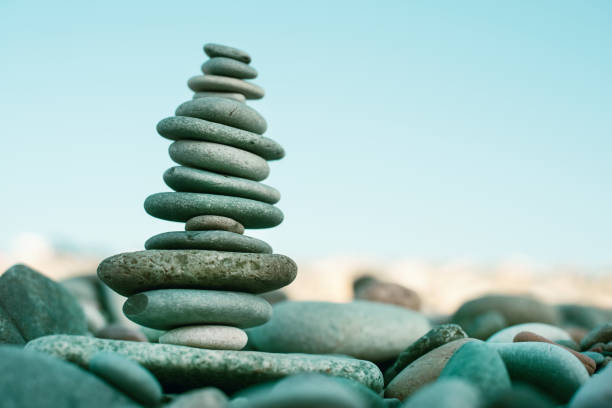 istock Stack of stones on beach - nature background. Stone cairn on green blurry background, pebbles and stones. Concept balance 1126638259