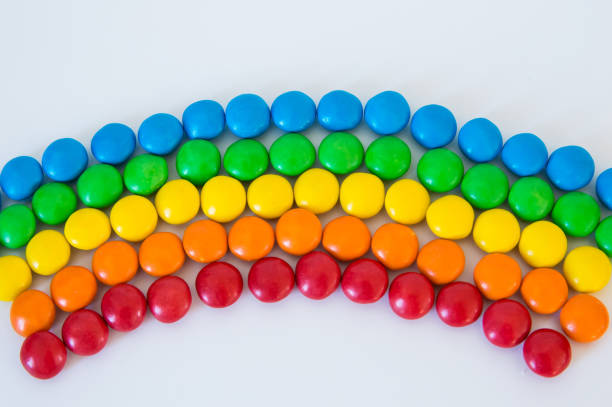 multicolored rainbow made of round colored dragee sweets lies on a white background