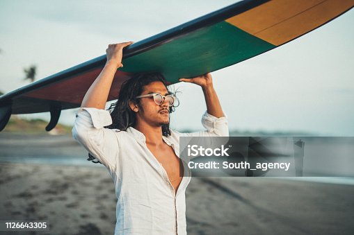 istock Guy with surfboard on the beach 1126643305