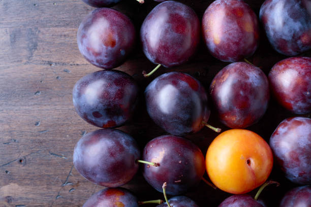 istock Ripe juicy plums on a wooden background. 1126643952