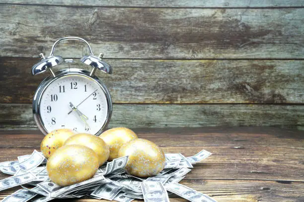 Photo of selective focus golden  eggs and gold on artificial US dollars and time