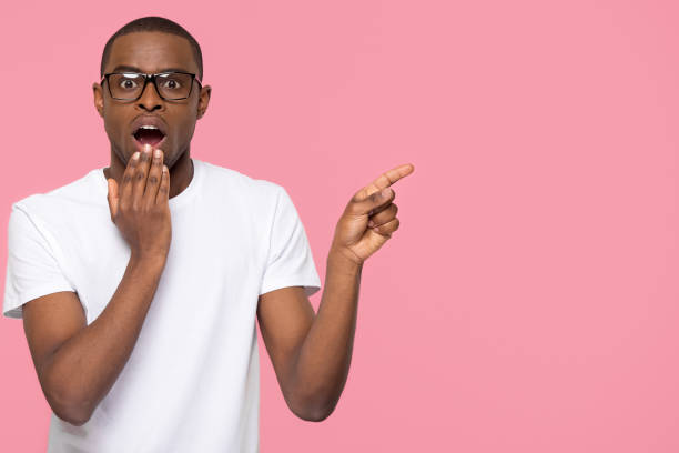 istock Shocked black man with open mouth pointing at copyspace aside 1126649032