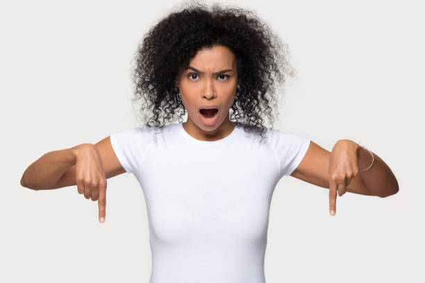 istock Shocked black woman looking at camera pointing fingers below 1126649071