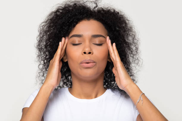 Nervous african woman breathing calming down trying to relieve stress Nervous african woman breathing calming down relieving headache or managing stress, black girl feeling stressed self-soothing massaging temples exhaling isolated on white grey studio blank background relief emotion photos stock pictures, royalty-free photos & images