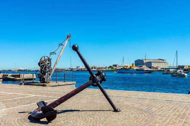 Denmark with an anchor on the quayside in the foreground and a recycling plant in the background.